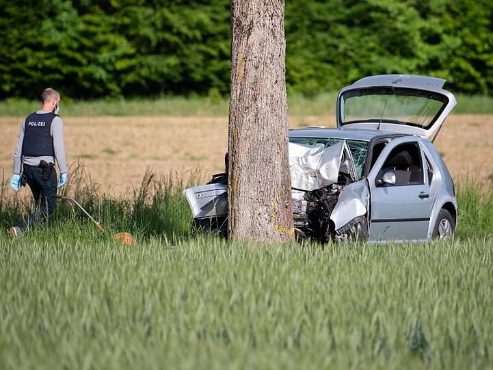 Ein Polizist geht auf ein zerstörtes Auto an einer Unfallstelle zu. Foto: Sven Hoppe/dpa