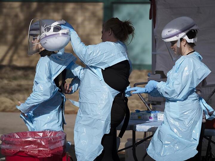 Im Kampf gegen die Lungenkrankheit: Gesundheitsmitarbeiter ziehen ihre Schutzkleidung an, bevor Menschen auf das neue Coronavirus getestet werden.