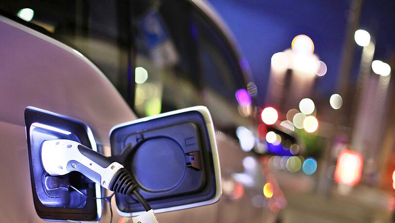 Ein elektrisch angetriebener BMW i3 lädt am Abend an einer Ladesäule.