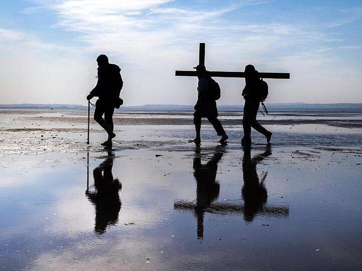 Pilger tragen während der Osterwallfahrt ein Kreuz zur Heiligen Insel Lindisfarne an der Nordostküste Northumberlands.