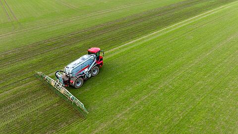 Ein Landwirt bringt Gülle im sogenannten Schleppschuh Verfahren auf einem Feld aus.
