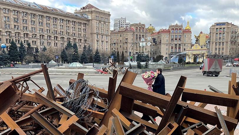Am Valentinstag läuft ein Mann mit einem Blumenstrauß in der Hand auf dem Maidan-Platz in Kiew an Panzersperren vorbei.