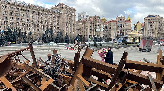 Am Valentinstag läuft ein Mann mit einem Blumenstrauß in der Hand auf dem Maidan-Platz in Kiew an Panzersperren vorbei.