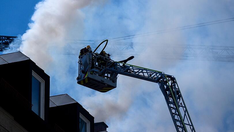 Feuerwehrleute stehen in der Schulstraße bei dem Wohnungsbrand auf einer Drehleiter.