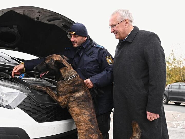 Innenminister Joachim Herrmann (CSU, r) mit einem Polizeibeamten und Hund Max bei einer Kontrolle. Foto: Nicolas Armer/dpa