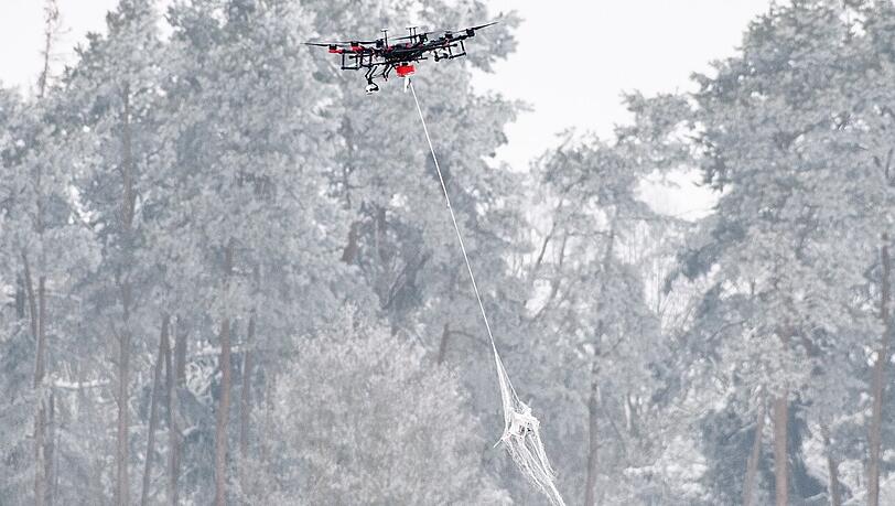 Eine Jagddrohne vom Typ AirRobot AR200 transportiert auf einem Präsentationstag der Bundeswehr zum Aufspüren und Abwehren von Drohnen eine handelsübliche kleine Drohne, die sie zuvor mit einem abgeworfenen Netz gefangen hat.