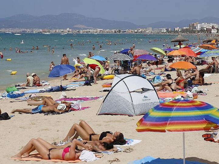 Touristen sonnen sich am Strand von El Arenal, einem der Hauptziele für deutsche und niederländische Touristen während der Sommersaison auf Mallorca.