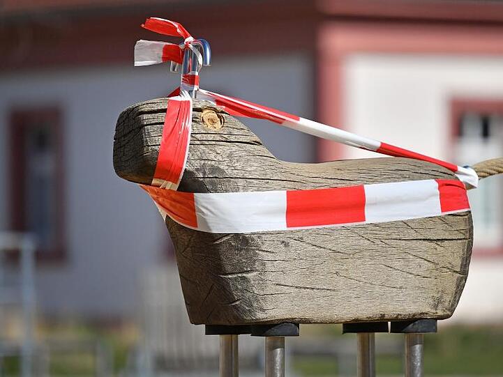 Mit rot-weißem Absperrband ist ein Spielgerät in Thüringen umwickelt, weil der Spielplatz gesperrt ist.
