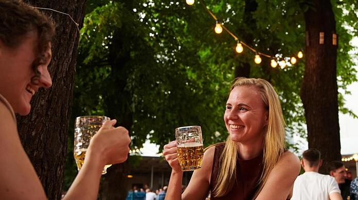 Zwei Frauen trinken ein Bier im Prater Biergarten in Berlin.