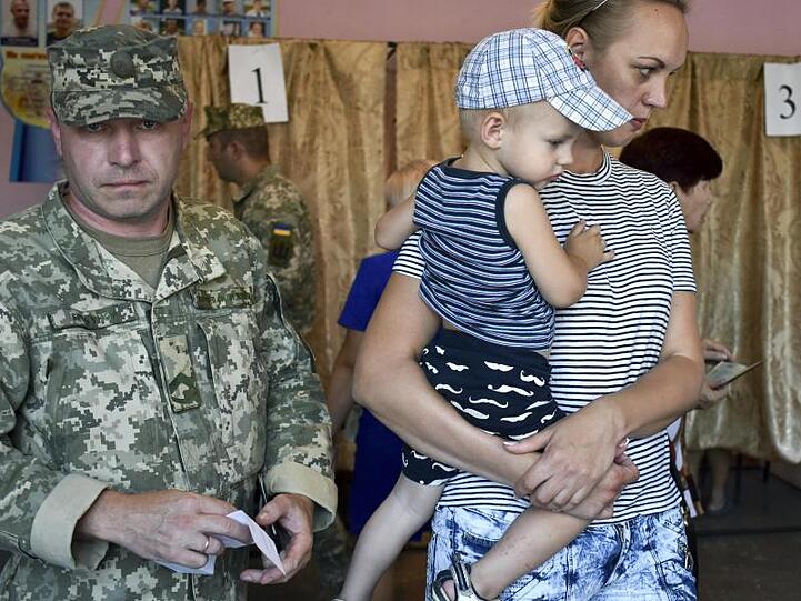 Ein Soldat und eine Frau mit einem Kind kommen in ein Wahllokal in Kramatorsk. Die Partei von Staatschef Selenskyj, Sluha Narodu, tritt mit dem Wahlversprechen an, den Krieg im Osten des Landes zu beenden.