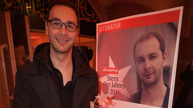 Autor Pierre Jarawan vor seinem "AZ-Literaturstern"-Poster.