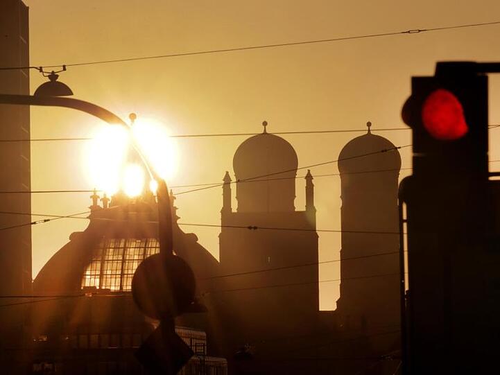 Die Sonne geht hinter den Türmen von Justizpalast und Frauenkirche (r) auf. Foto: Stephan Jansen/dpa/Archivbild