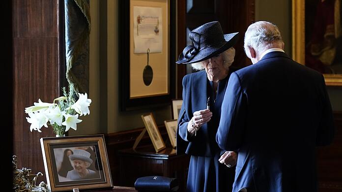 Königin Camilla hält einen Füllfederhalter, während sich König Charles III. Tinte von der Hand wischt. Der Monarch wollte sich in Hillsborough Castle in ein Gästebuch eintragen, als der Stift zu schmieren begann.