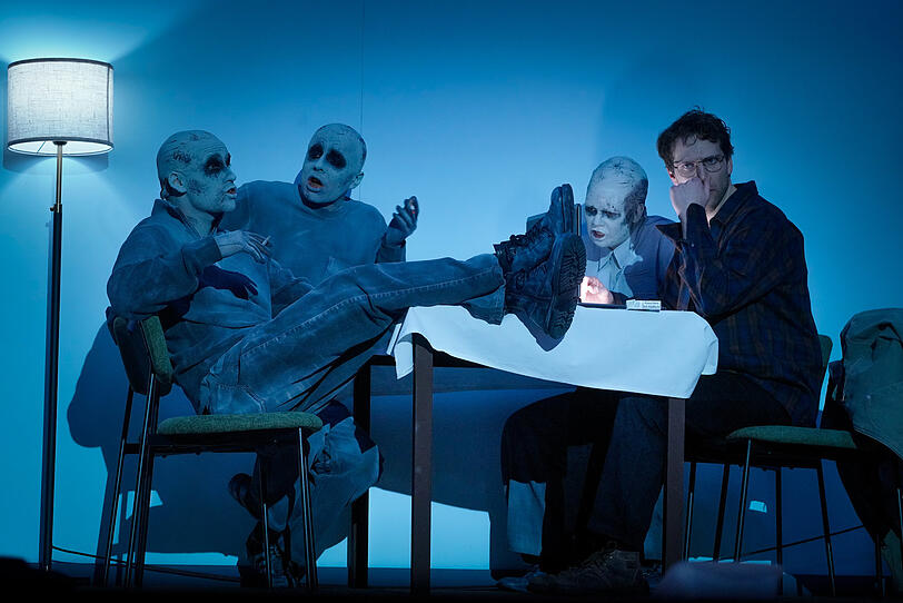 Zombiehaft wirkt das Sextett, die K&ouml;pfe kahl, verschorft, ihre Kleidung variantenreich.  Die sechs Darstellenden sind Julian Gutmann, Maximiliane Ha&szlig;, Alexandros Koutsoulis, Jonathan M&uuml;ller, Anton N&uuml;rnberg und Baran S&ouml;nmez.