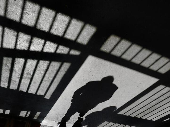 Ein Schatten hinter Gittern einer JVA. Foto: Felix Kästle/dpa/Archivbild