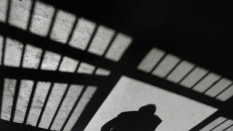 Ein Schatten hinter Gittern einer JVA. Foto: Felix Kästle/dpa/Archivbild
