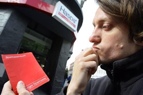 Bankkunde vor einer Sparkasse: Ist mein Erspartes noch sicher?