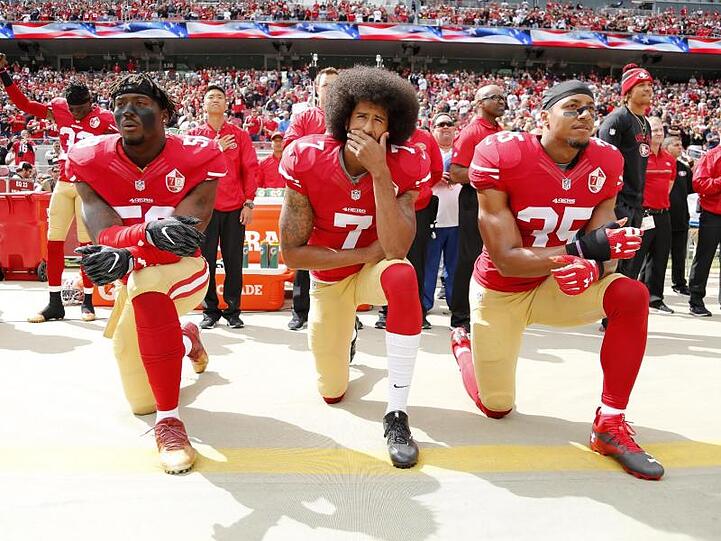 Colin Kaepernick (M.) kniete 2016 mit seinen Teamkollegen Eli Harold (l) und Eric Reid vor einem Spiel der San Francisco 49ers.