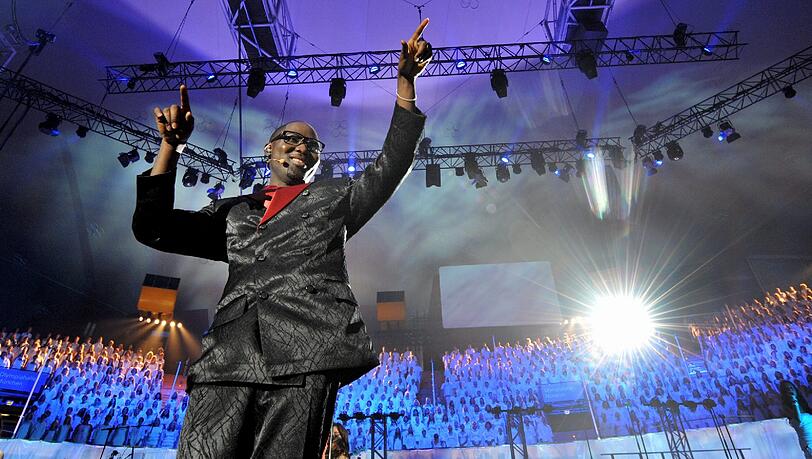 Ein Lied, ein Dirigent und 1198 Sänger. Beim Song "Hold on" dirigiert Mano Ezoh den Gospelchor in der Münchner Olympiahalle zum Weltrekord. Ein Lied, ein Dirigent und 1198 Sänger. Beim Song "Hold on" dirigiert Mano Ezoh den Gospelchor in der Münchner Olympiahalle zum Weltrekord.