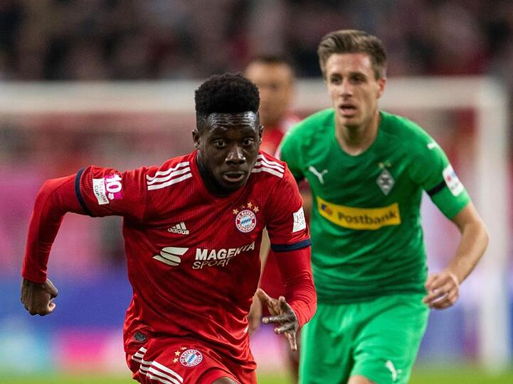 Bayerns Alphonso Davies und Gladbachs Patrick Herrmann (l-r.) bemühen sich um den Ball. Foto: Marius Becker