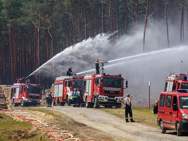 Die Feuerwehr spritzt das Löschwasser seitlich in den Wald.
