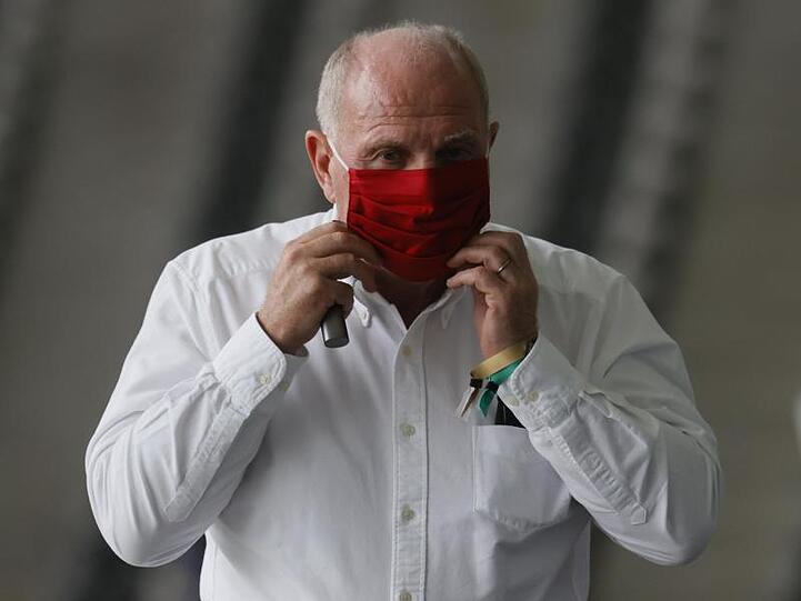 Uli Hoeneß, ehemaliger Präsident von Bayern München, zieht den Mundschutz zurecht. Foto: Ronald Wittek/epa/Pool/dpa/Archivbild