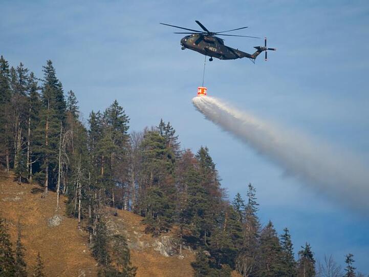 Ein Hubschrauber mit einem Wassertank überfliegt den Schwarzberg. Foto: Sven Hoppe/dpa/Archivbild