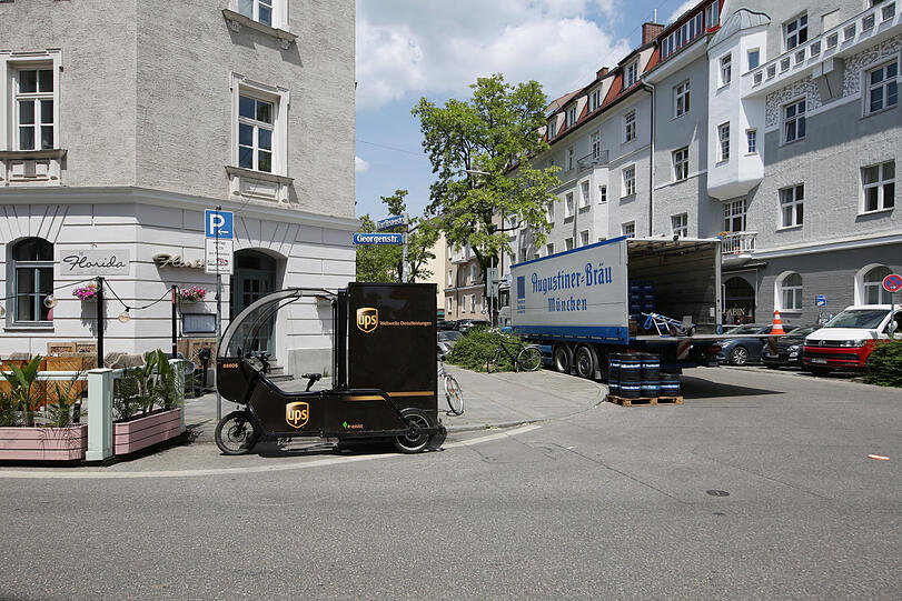 Der große Augustinerlaster mit alter Schrift parkt mit Warnblinkanlage, links davon ein Lastenrad. Ein urbanes Stilleben.