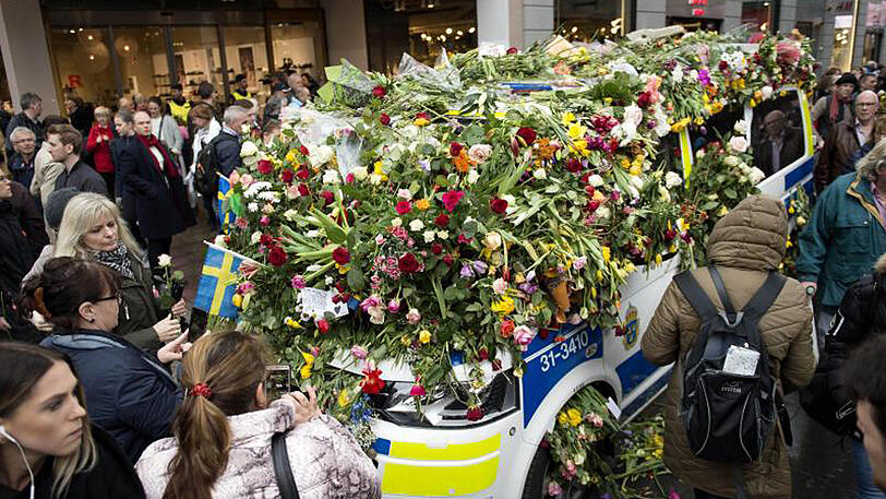 Ein Polizeifahrzeug ist in der Innenstadt von Stockholm nach dem mutmaßlichen Terroranschlag fast vollständig mit Blumen bedeckt.