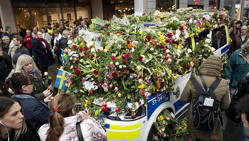 Ein Polizeifahrzeug ist in der Innenstadt von Stockholm nach dem mutmaßlichen Terroranschlag fast vollständig mit Blumen bedeckt. Ein Polizeifahrzeug ist in der Innenstadt von Stockholm nach dem mutmaßlichen Terroranschlag fast vollständig mit Blumen bedeckt.
