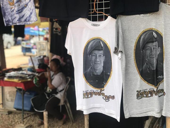 Vor der Tham-Luang-Höhle im äußersten Norden Thailands werden T-Shirts verkauft, auch mit dem Porträt des Ex-Marinetauchers Saman Kunan.