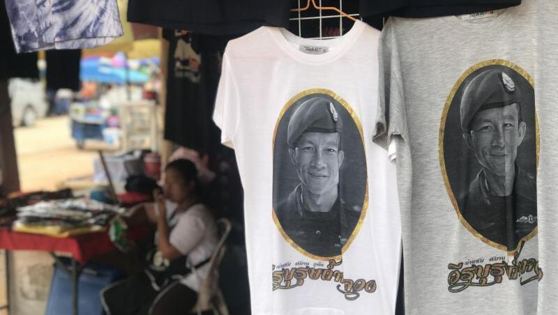 Vor der Tham-Luang-Höhle im äußersten Norden Thailands werden T-Shirts verkauft, auch mit dem Porträt des Ex-Marinetauchers Saman Kunan. Vor der Tham-Luang-Höhle im äußersten Norden Thailands werden T-Shirts verkauft, auch mit dem Porträt des Ex-Marinetauchers Saman Kunan.