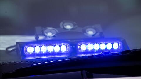 Ein Blaulicht leuchtet unter der Frontscheibe eines Einsatzfahrzeugs der Polizei.