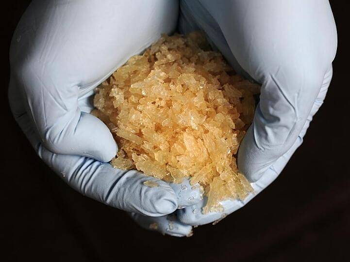 Ein Ermittler des Bundeskriminalamtes hält bei einer Pressekonferenz die Droge Crystal in seinen Händen. Foto: Fredrik von Erichsen/Archiv