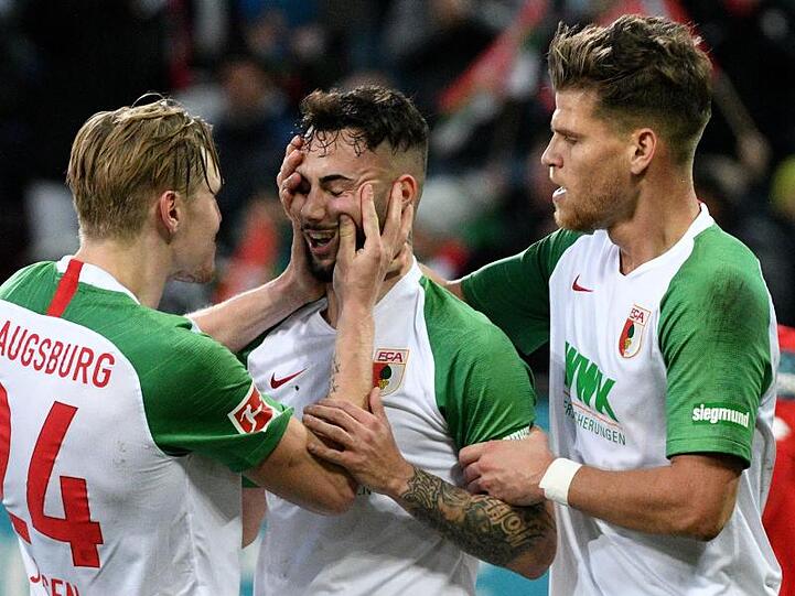 Augsburgs Fredrik Jensen (l) und Florian Niederlechner (r) freuen sich mit Torschütze Marco Richter über den Führungstreffer.