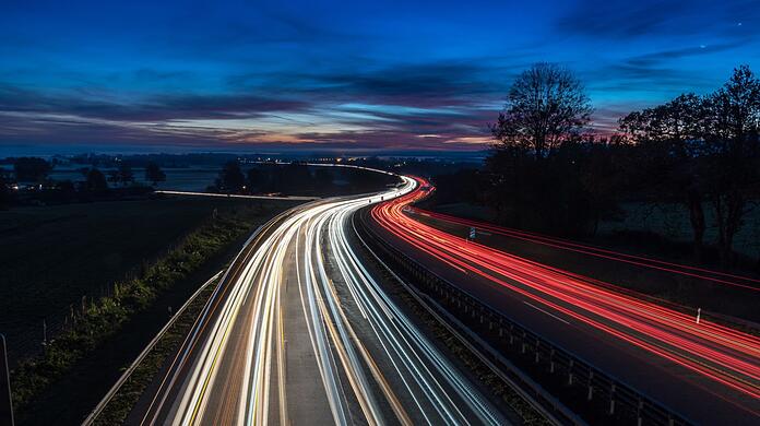 Autos fahren über die Autohbahn A8 bei Bernau am Chiemsee während die Sonne aufgeht.