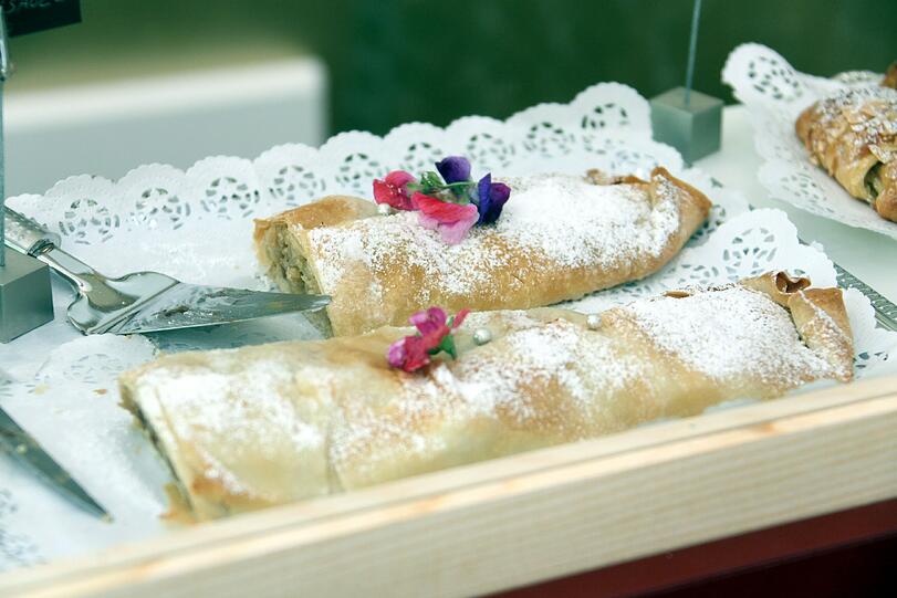 Mit essbaren Blüten garniert: Der warme Wiener Apfelkuchen. Serviert wird er mit Vanillesauce.