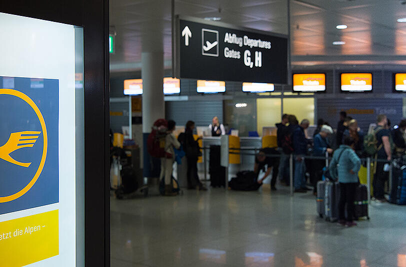 Fluggäste stehen am Montagmorgen am Münchner Flughafen am Lufthansa-Schalter.