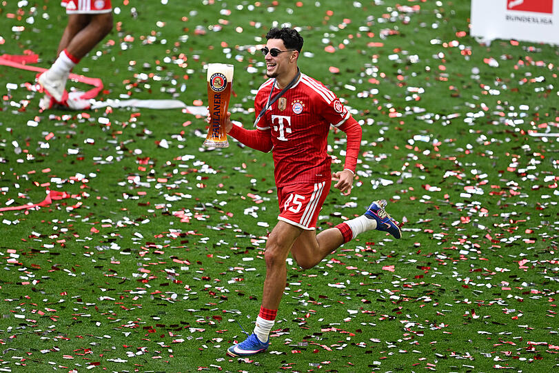 Aleksandar Pavlovic sprintet bei der Meisterfeier mit einem Glas Bier &uuml;ber den Rasen.