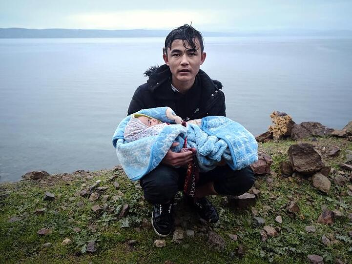 Ein Migrant hält ein Baby an der Küste der griechischen Insel Lesbos, nachdem er mit einem Schlauchboot von der Türkei aus über das Mittelmeer gekommen ist.