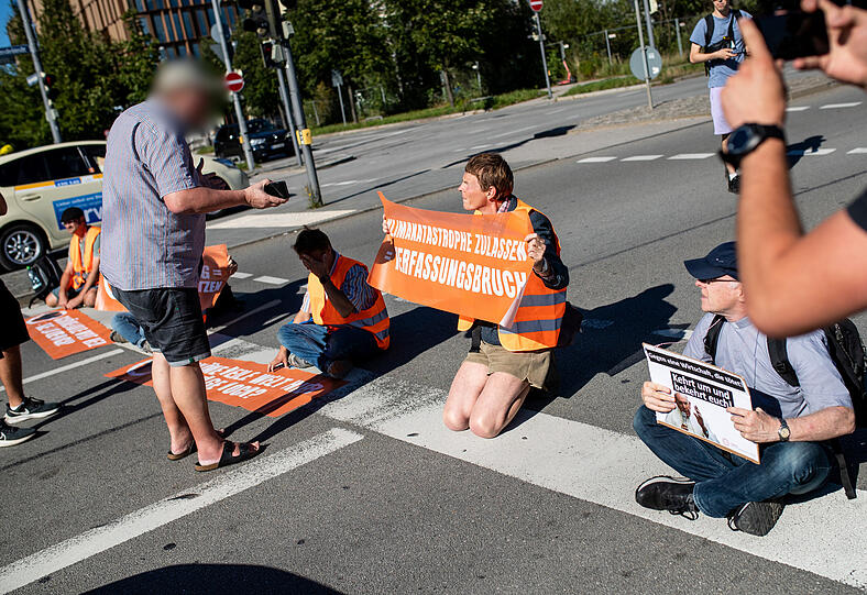 Der Autofahrer spricht mit den Klimaaktivisten. Im Video ist zu sehen, wie er einen der Protestierenden ohrfeigt.