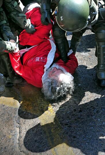 Auch Weihnachtsmänner dürfen nicht alles: Ein Demonstrant wird in Santiago de Chile etwas ruppig festgenommen.