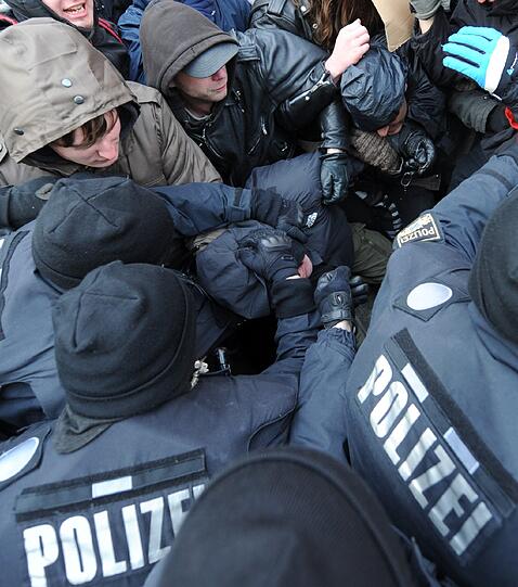 Es kommt zum Gerangel zwischen Demonstranten und der Polizei. Die Polizei greift nach den Demonstranten.