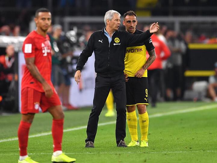 Dortmunds Trainer Lucien Favre (M) gibt Stürmer Paco Alcacer Anweisungen. Links steht Bayerns Thiago.