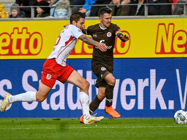 Marco Grüttner von Regensburg und Waldemar Sobota von St. Pauli (l-r.) bemühen sich um den Ball. Foto: Armin Weigel/dpa