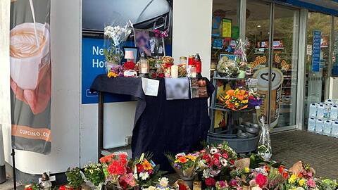 Menschen haben Blumen und Kerzen am Tatort abgelegt.