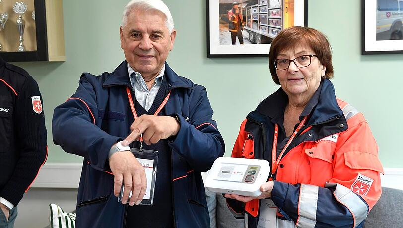 Malteser-Technikexperte Victor Blaga und Malteser-Not-Helferin Karin Simon zeigen den Armbandsender und den Lautsprecher für das Notrufsystem. Malteser-Technikexperte Victor Blaga und Malteser-Not-Helferin Karin Simon zeigen den Armbandsender und den Lautsprecher für das Notrufsystem.