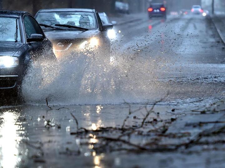 Autos fahren durch eine tiefe Pfütze. Foto: Caroline Seidel/Archivbild