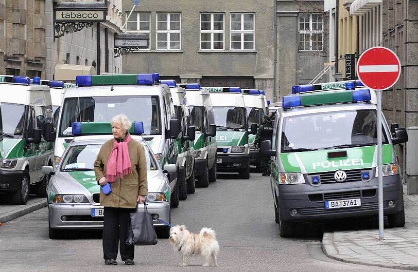 Eine einsame Passantin mit Hund - und dahinter Polizei, soweit das Auge reicht: Die Innenstadt wird mit tausenden Polizisten abgesichert. (Archivbild)