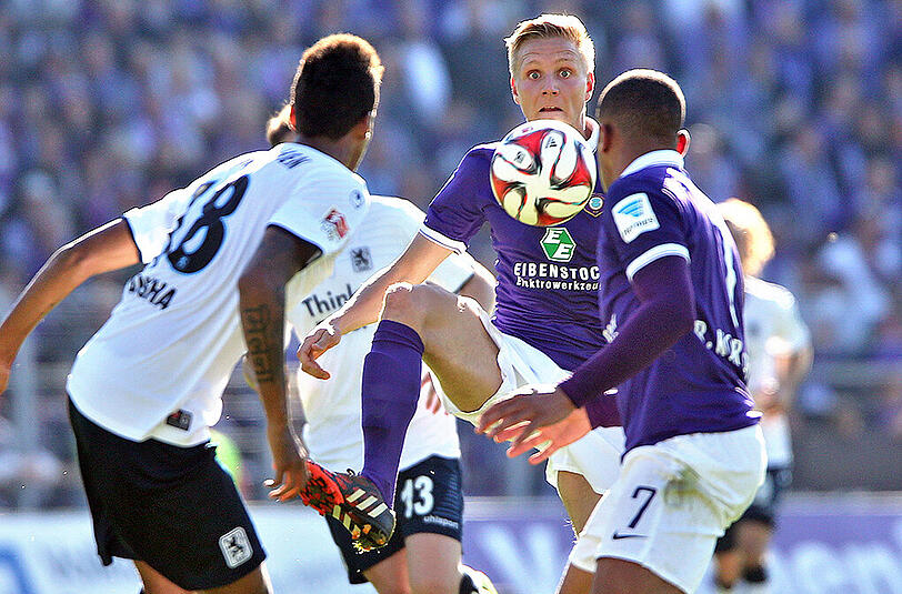 Aues Dorian Diring (M.) und Romario Kortzorg (r) sowie Münchens Martin Angha (l) kämpfen um den Ball.